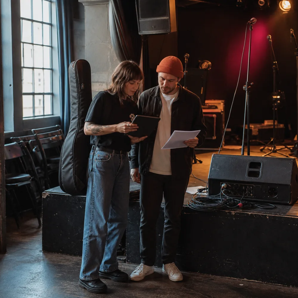 Independent artist and venue booking manager reviewing show details during soundcheck